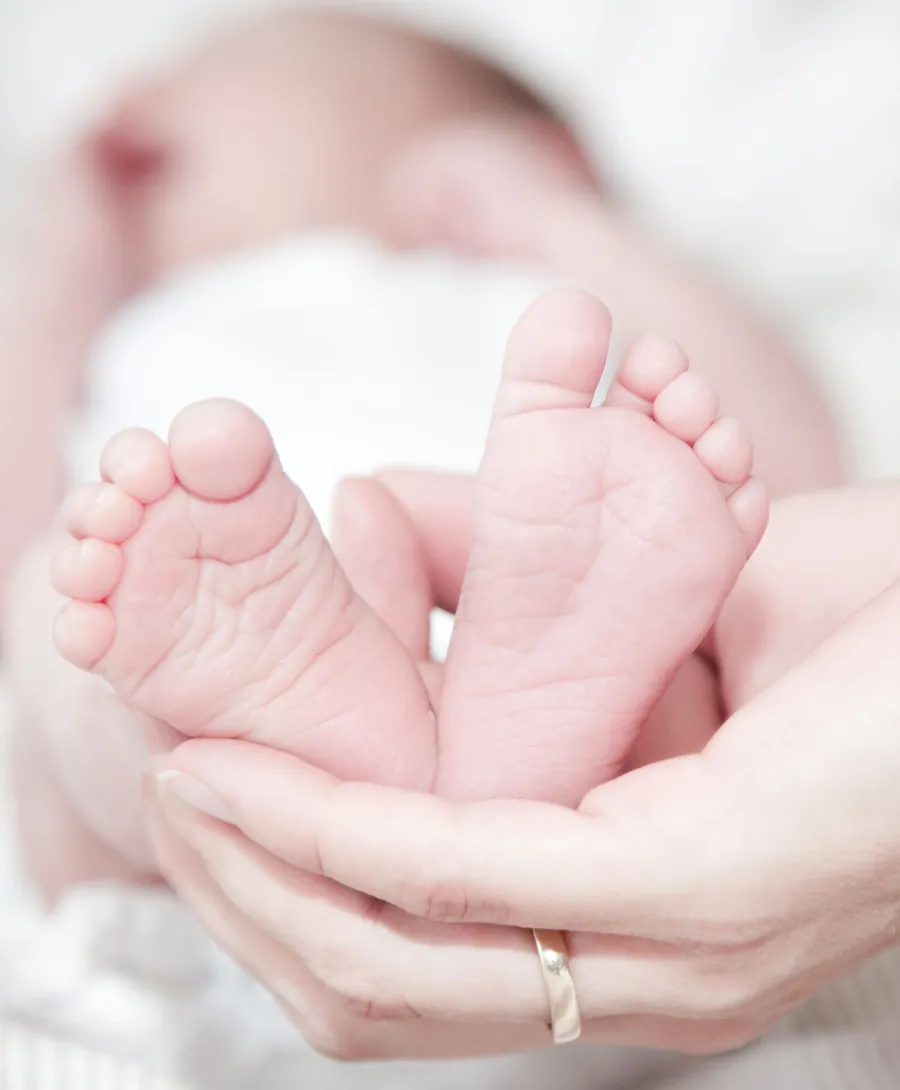 Voetjes van een pasgeboren baby in de handen van een volwassene