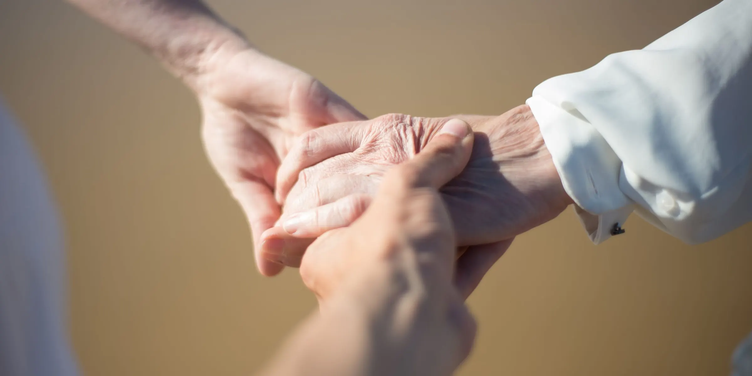 Een zorgverlener houdt de hand van een oudere vrouw vast