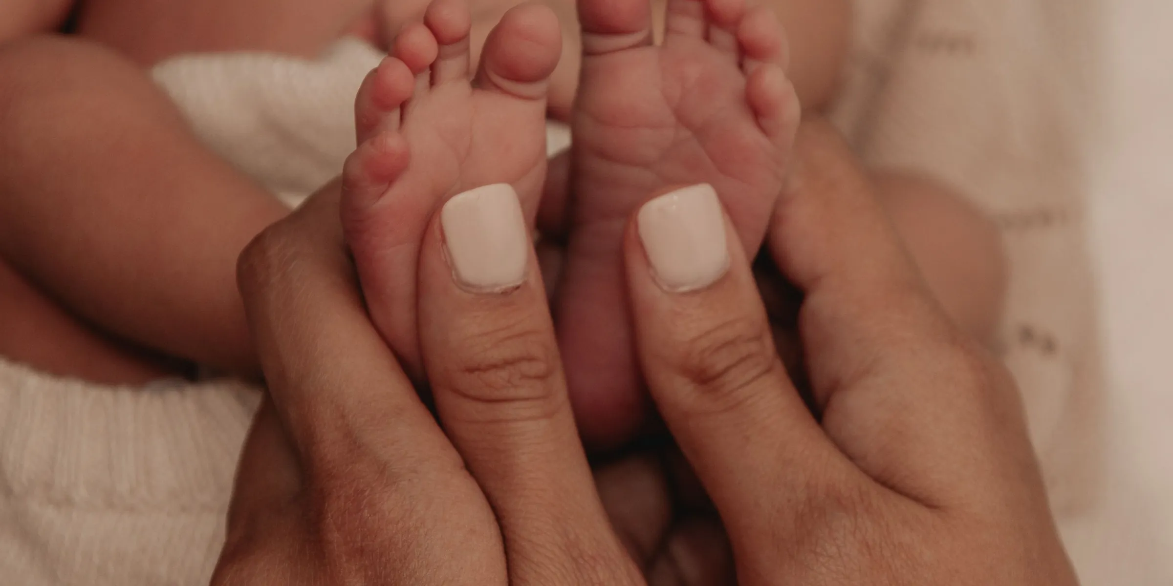 Handen van ouders rond de voetjes van een pasgeboren baby