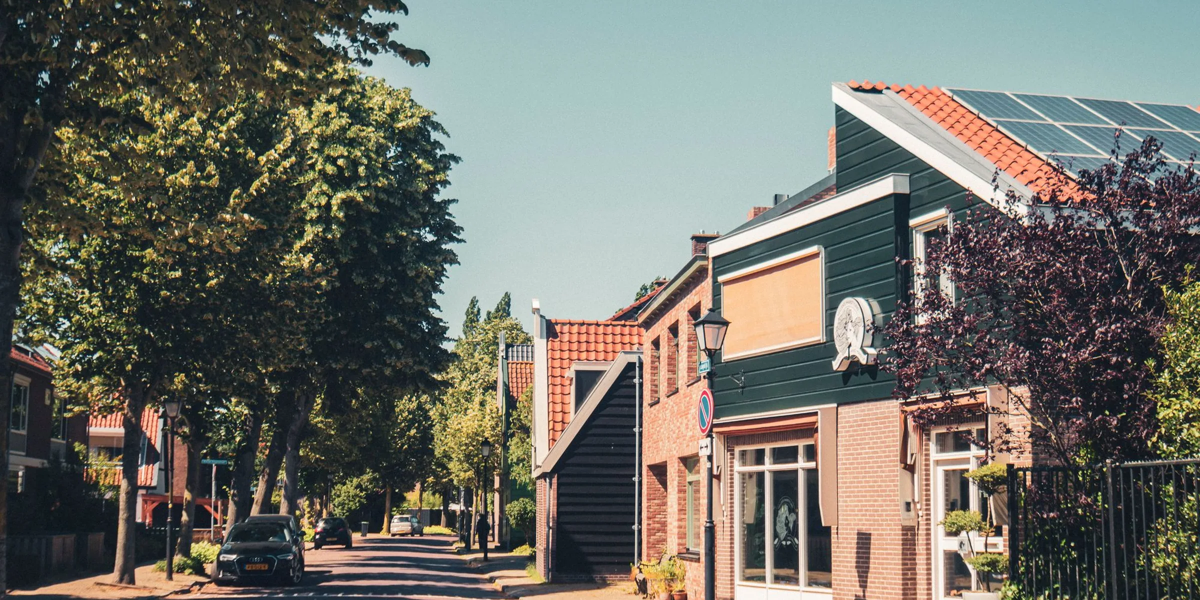 Rustige woonstraat met rijtjeshuizen en bomen op een zomerse dag