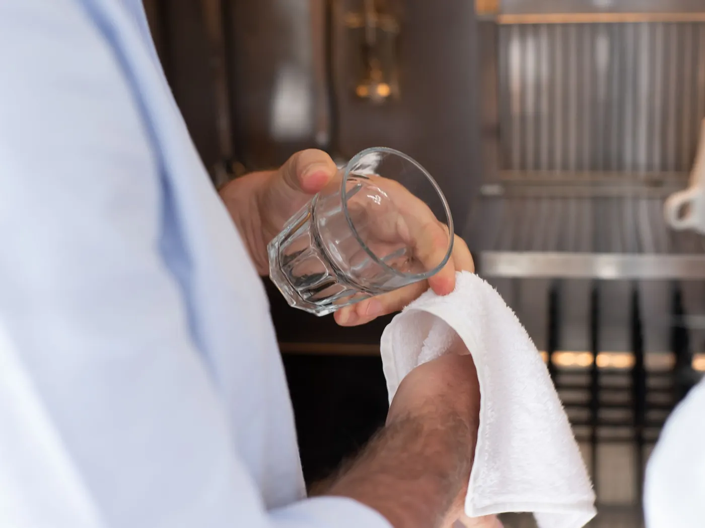 Een glas wordt met een doek drooggewreven in de keuken