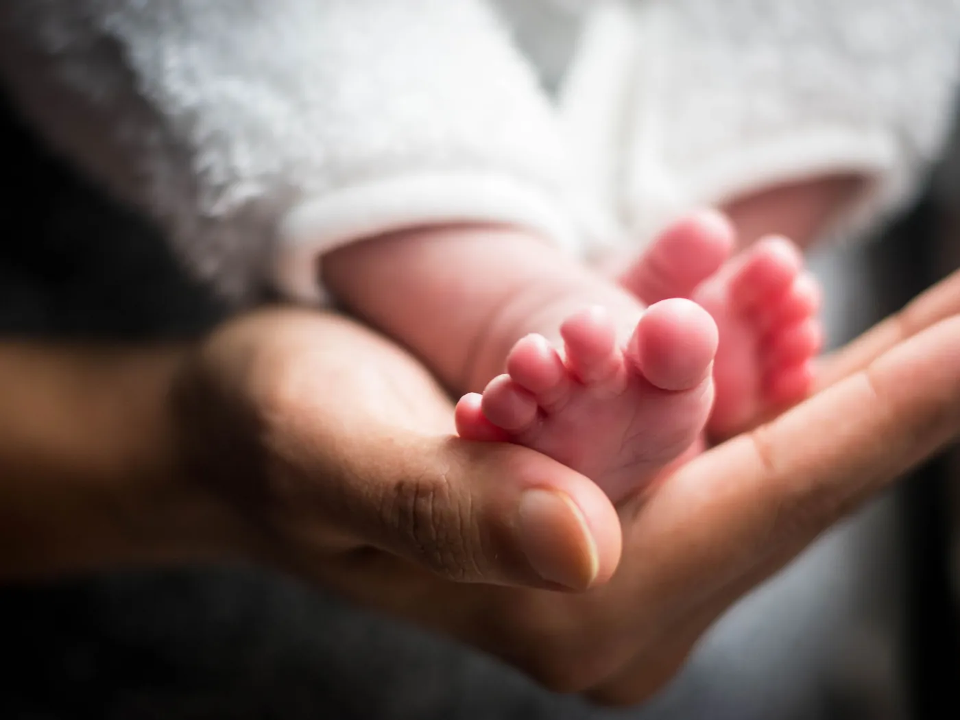 Een voetje van een pasgeboren baby in de handen van een volwassene