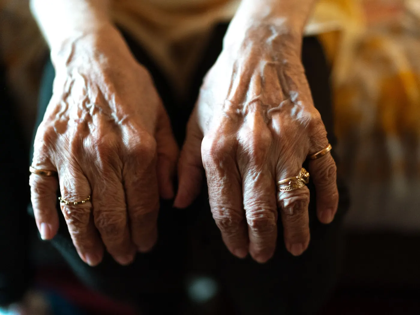 Oudere handen met ringen rusten in de schoot