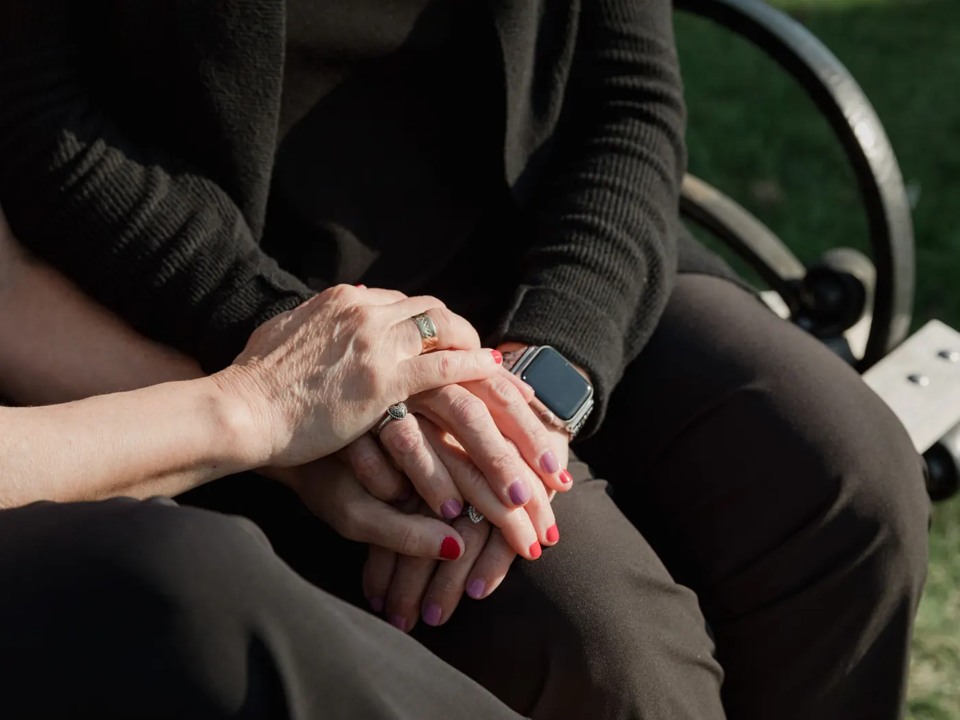 Een zorgverlener legt haar hand op de handen van een oudere vrouw