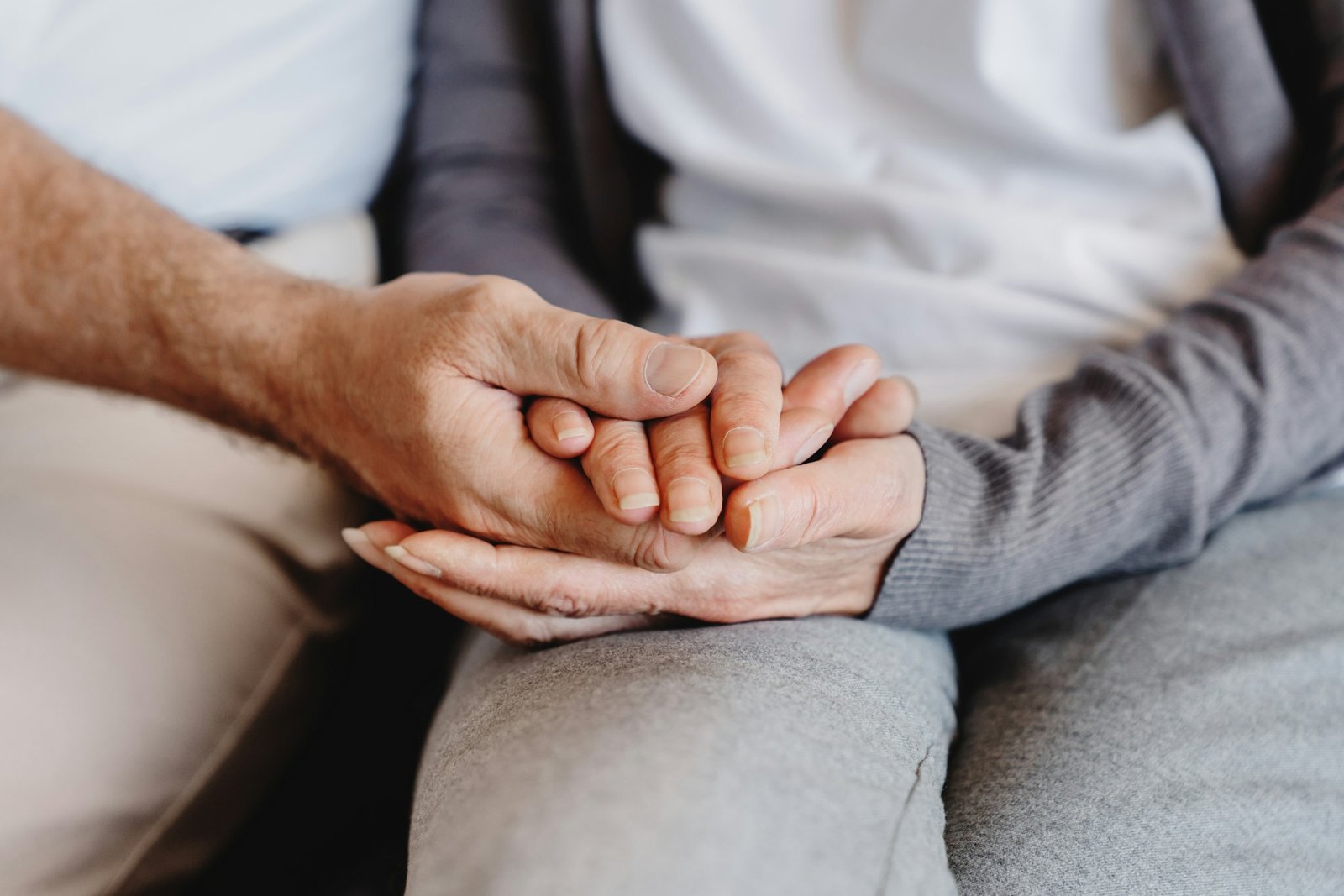 Close up elder family couple sitting on sofa, holding hands, taking care of each other.